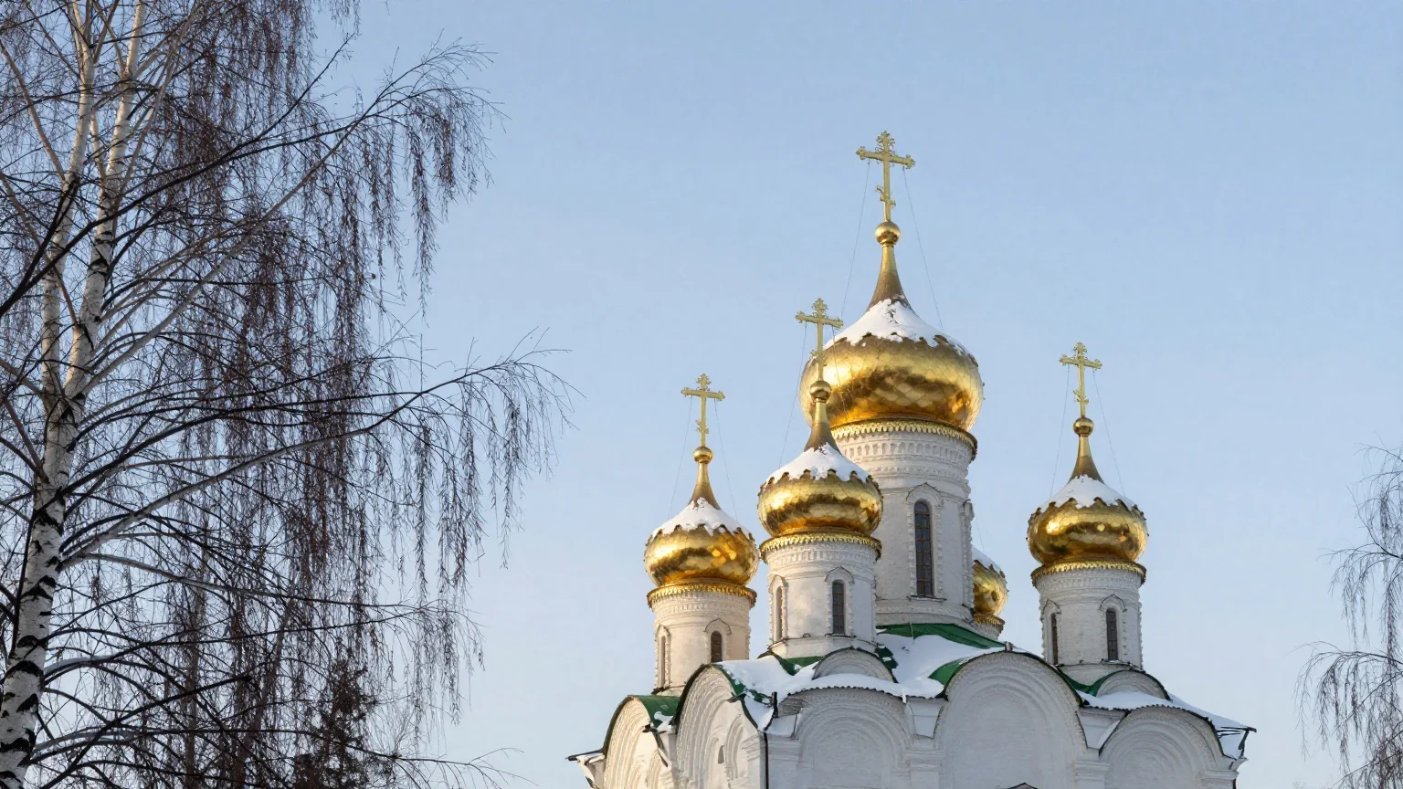 Goldene Zwiebelkuppeln einer orthodoxen Kirche mit Schnee vor klarem Winterhimmel