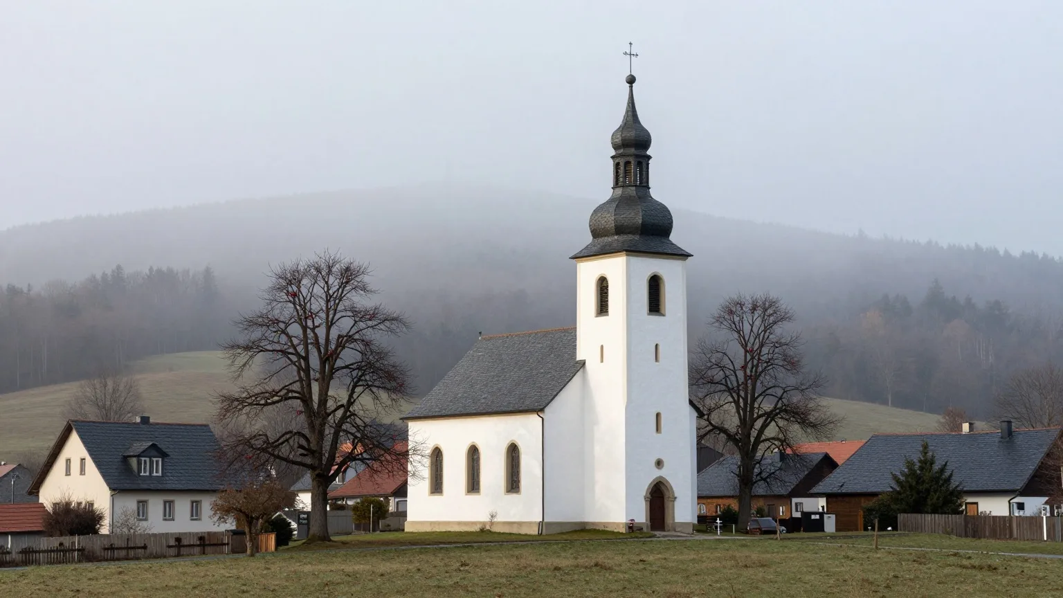 Schlichte Dorfkirche mit Schieferturm an einem nebligen Novembermorgen im Erzgebirge