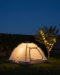 Von innen leuchtendes Zelt auf einer Gartenwiese in der Nacht