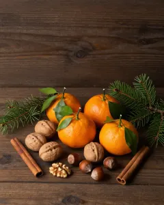 Mandarinen mit Blättern, Walnüsse und Haselnüsse auf einem dunklen Holztisch