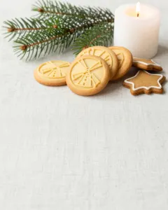 Spekulatius und Lebkuchen auf hellem Leinen mit Tannenzweig und brennender Kerze