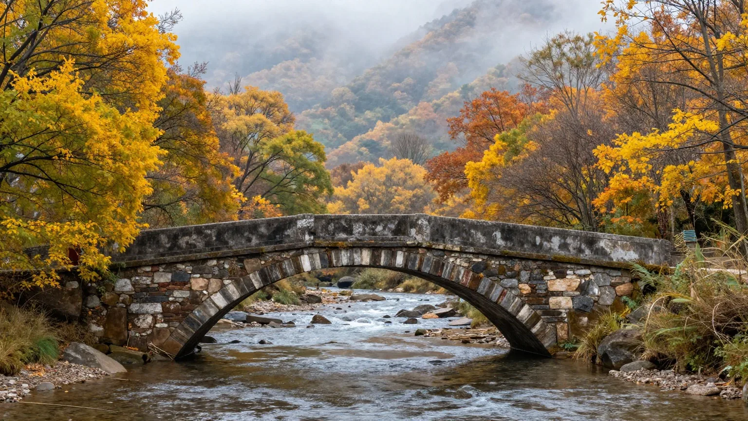 Alte Steinbogenbrücke über einen Fluss im frühherbstlichen Morgennebel
